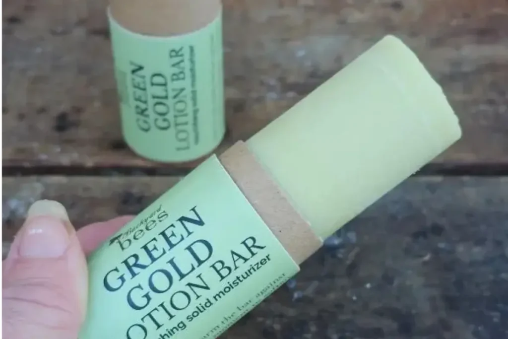 Green Gold lotion bar by Backyard Bees, photographed on natural wood with herbs.