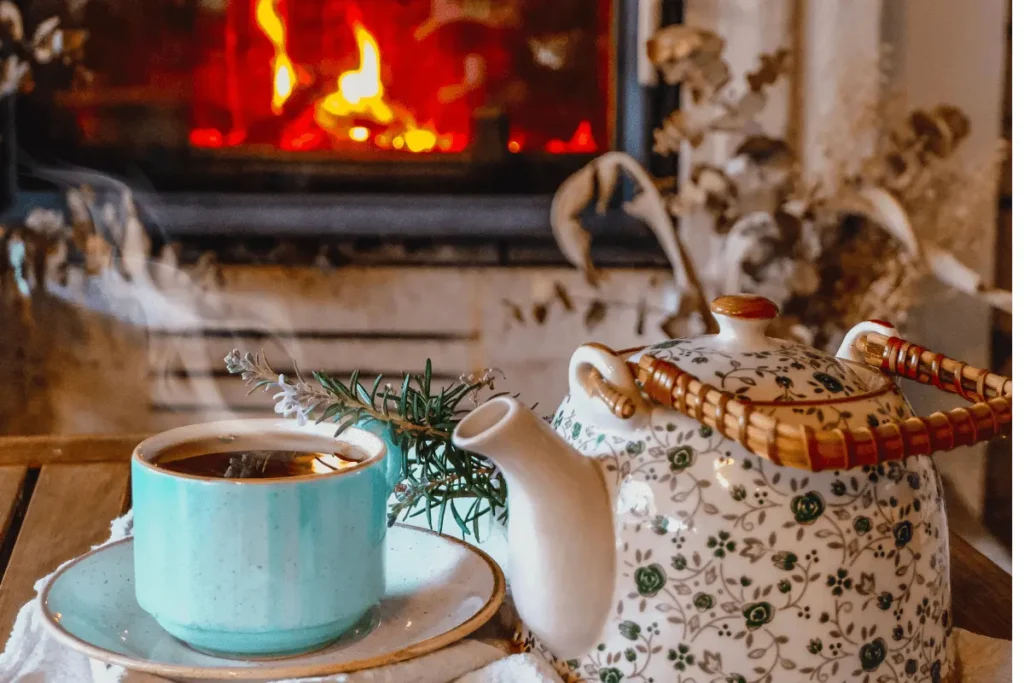 A steaming cup of herbal tea beside a fireplace on a winter evening, reflecting quiet solstice rituals and warmth.